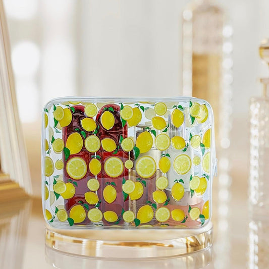 Lemon-print clear cosmetic bag filled with skincare and beauty products on a vanity table.