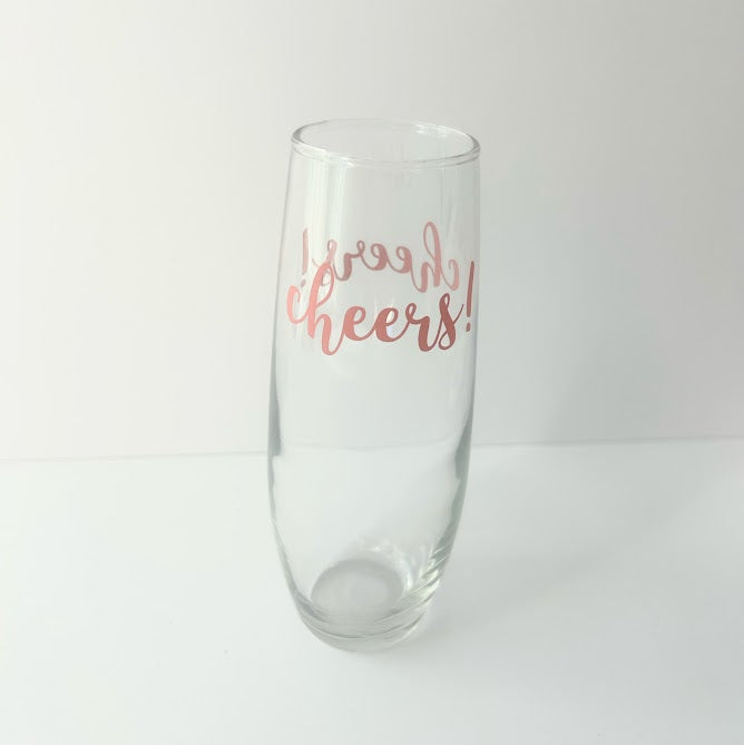 Clear champagne flute with pink "Cheers!" lettering, perfect for champagne gifts, hostess gifts, bridal showers, birthdays, and celebration wellness gift bundles.