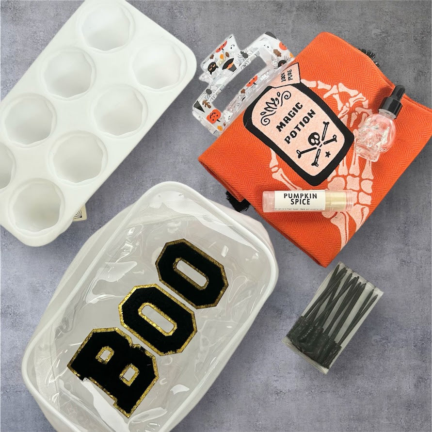 Black BOO Halloween Wellness Gift Bundle with orange Magic Potion towel, pumpkin spice lip balm, skull bottle, ice mold, hair clip and seasonal accessories.