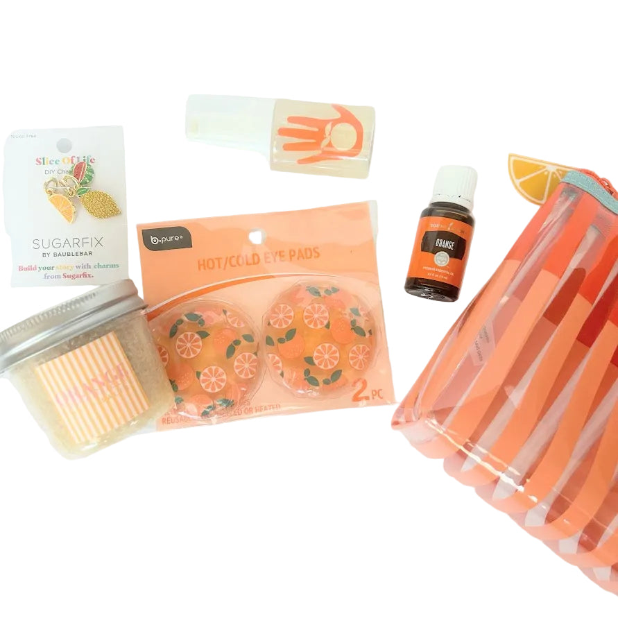 Orange-themed wellness gift for her with essential oil, bath products, citrus accessories and reusable gift bag