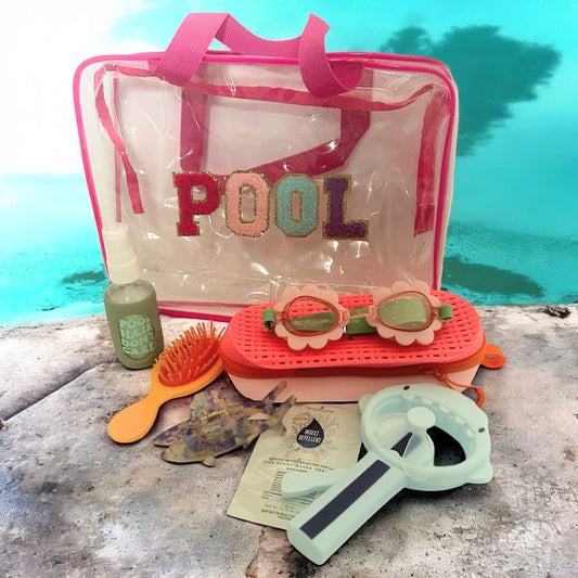 Pool-themed items including a clear bag with 'POOL' text, goggles, brush, and other accessories on a swimming pool deck.