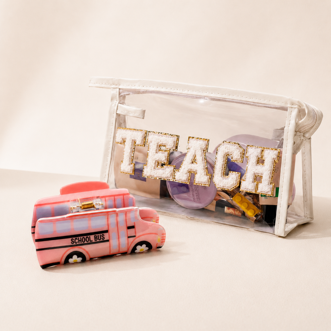 Back-to-school teacher wellness gift bundle featuring clear TEACH cosmetic bag and fun school bus hair accessory.

Alternative: