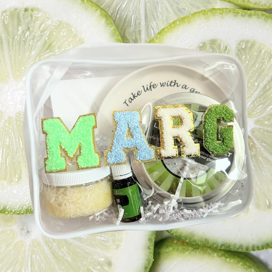 Margarita-inspired wellness gift featuring margarita salt, citrus body scrub, lime essential oil, and reusable gift bag on a fresh lime background.