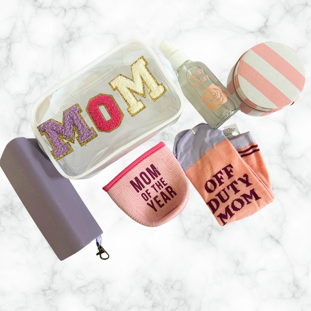 Flat lay of wellness gifts for moms including a clear MOM cosmetic bag, beauty accessories, socks, and self-care essentials.